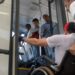Homem em cadeira de rodas tentando entrar em ônibus com ajuda, observado por três passageiros no interior