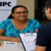 Beneficiária durante entrevista de averiguação do Cadastro Único, com a equipe preenchendo o formulário e os cartões do BPC e do Bolsa Família sobre a mesa