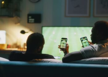 Apostadores acompanham jogo de futebol com aplicativos de apostas no celular, público atingido pelas novas regras de publicidade de bets