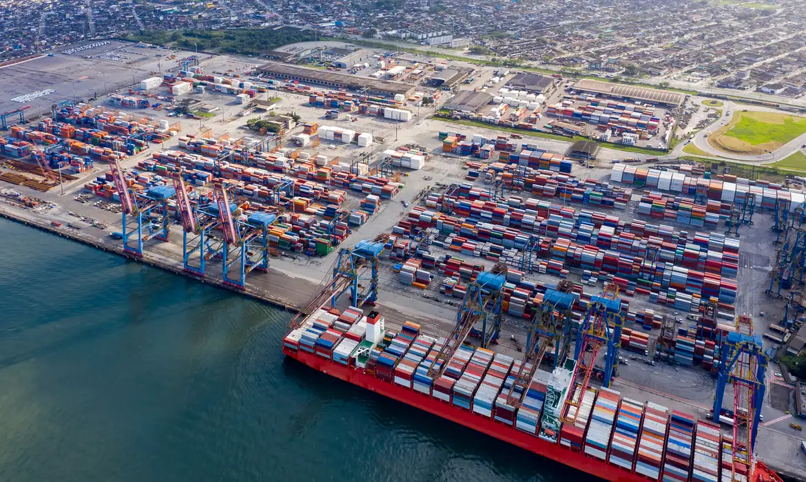 Vista aérea de um porto brasileiro cheio de contêineres, com navio de carga atracado, representando as exportações afetadas pelo tarifaço de 25% dos EUA