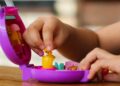 Mãos de uma criança manuseiam um brinquedo, ilustrando o alerta do Ministério da Justiça sobre smart toys que captam dados sem transparência