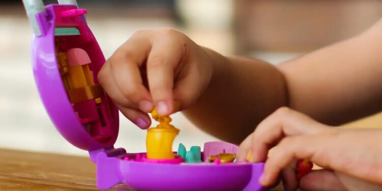 Mãos de uma criança manuseiam um brinquedo, ilustrando o alerta do Ministério da Justiça sobre smart toys que captam dados sem transparência