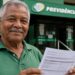 Homem idoso segura um documento em frente a uma agência da Previdência Social, ilustrando o calendário de pagamentos do INSS