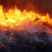 Incêndio florestal com labaredas e coluna de fumaça sobre a vegetação, cena que representa os focos de calor monitorados pelo Ministério da Saúde.