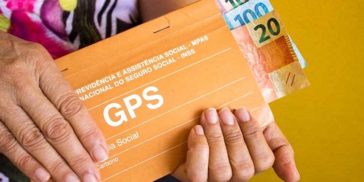 Mãos preenchendo guias GPS da Previdência Social para manter a qualidade de segurado do INSS