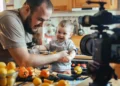 Pai grava vídeo com filho pequeno em ambiente doméstico para publicação na internet.
