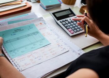 Pessoa faz contas com calculadora sobre documentos financeiros, ilustrando o crédito do Fies Empreendedor para quem quer empreender