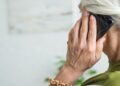 Mulher idosa de cabelos brancos fala ao telefone celular em casa, imagem que ilustra a matéria sobre o projeto que prevê devolução de valores a idosos vítimas de golpe digital