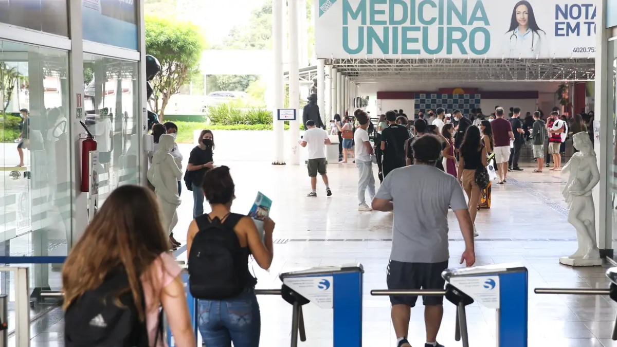 Estudantes caminham na entrada de uma faculdade particular, ilustrando as bolsas de estudo oferecidas pelo Prouni