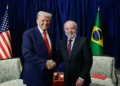 Lula e Donald Trump apertam as mãos diante das bandeiras do Brasil e dos Estados Unidos, simbolizando as relações comerciais e diplomáticas entre os dois países.