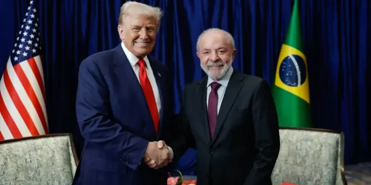 Lula e Donald Trump apertam as mãos diante das bandeiras do Brasil e dos Estados Unidos, simbolizando as relações comerciais e diplomáticas entre os dois países.