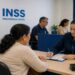 Imagem ilustrativa de atendimento em agência do INSS, com servidora preenchendo formulário para uma segurada, representando o mutirão de perícias e avaliações sociais.