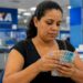 Beneficiária conta cédulas de real em agência da Caixa após o pagamento antecipado do Bolsa Família de julho de 2026 em cidades de seis estados