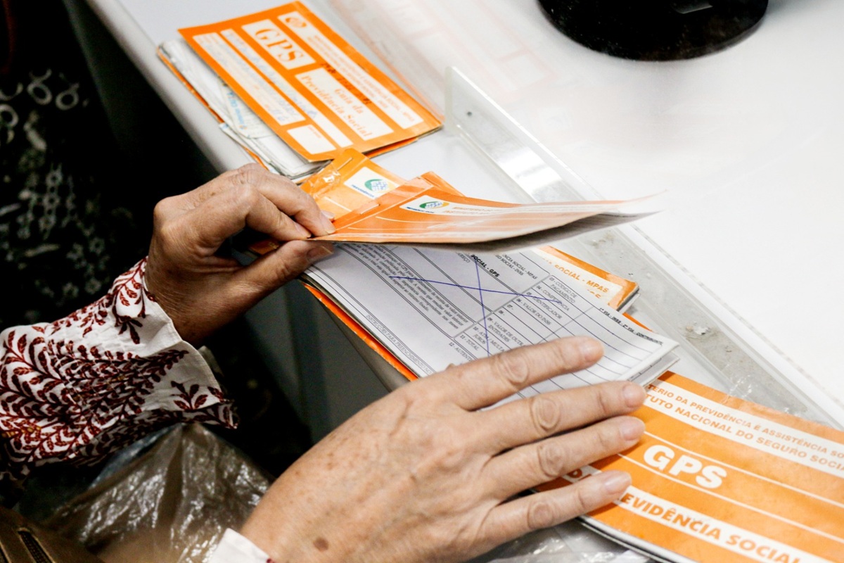 Pessoa segurando carnê GPS e dinheiro para manter em dia a qualidade de segurado do INSS