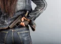 Mulher segurando uma arma de fogo na cintura, representando proposta que prevê porte temporário para mulheres com medida protetiva.