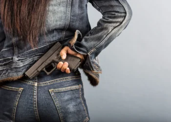 Mulher segurando uma arma de fogo na cintura, representando proposta que prevê porte temporário para mulheres com medida protetiva.