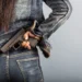Mulher segurando uma arma de fogo na cintura, representando proposta que prevê porte temporário para mulheres com medida protetiva.