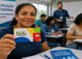 Mulher segura o cartão do Bolsa Família em uma sala de curso de qualificação profissional, ilustrando o projeto que prevê auxílio para estudar