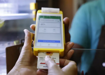 Cliente insere cartão de vale-alimentação em maquininha amarela durante pagamento em estabelecimento comercial