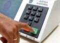 Eleitor pressiona a tecla confirma da urna eletrônica, em referência às regras de quem vota fora do domicílio eleitoral em 2026