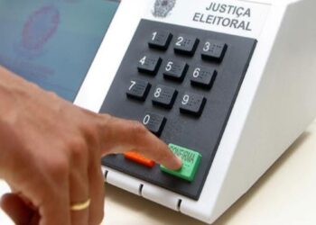 Eleitor pressiona a tecla confirma da urna eletrônica, em referência às regras de quem vota fora do domicílio eleitoral em 2026