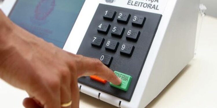 Eleitor pressiona a tecla confirma da urna eletrônica, em referência às regras de quem vota fora do domicílio eleitoral em 2026
