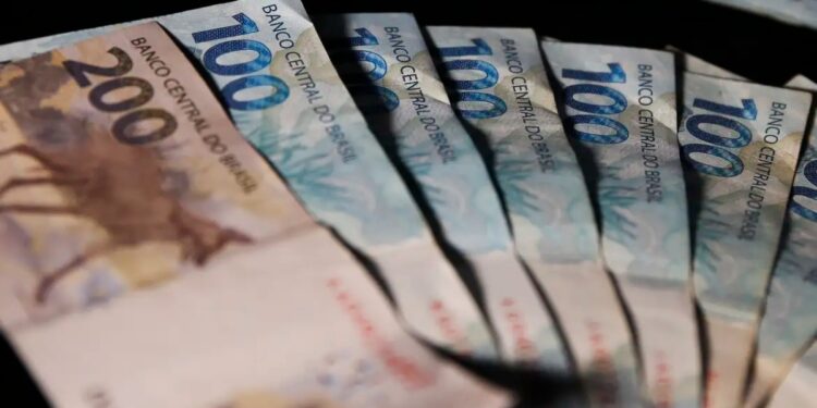 Notas de R$ 100 e R$ 200 espalhadas, representando o dinheiro do cashback do Imposto de Renda pago pela Receita Federal
