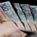 Notas de R$ 100 e R$ 200 espalhadas, representando o dinheiro do cashback do Imposto de Renda pago pela Receita Federal