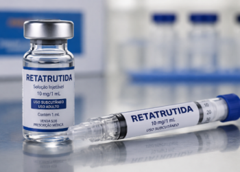 Frasco e seringa de Retatrutida 10mg/1mL sobre superfície metálica com fundo desfocado de frascos