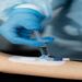 Profissional de luvas aplica uma seringa em um acesso na veia do braço de um paciente, cena que ilustra a matéria sobre o alerta da Anvisa contra a soroterapia em pessoas saudáveis
