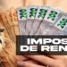 Imagem ilustrativa com leão símbolo do Imposto de Renda e mão segurando notas de real, representando o terceiro lote de restituição do IRPF 2026 que entra em consulta nesta sexta