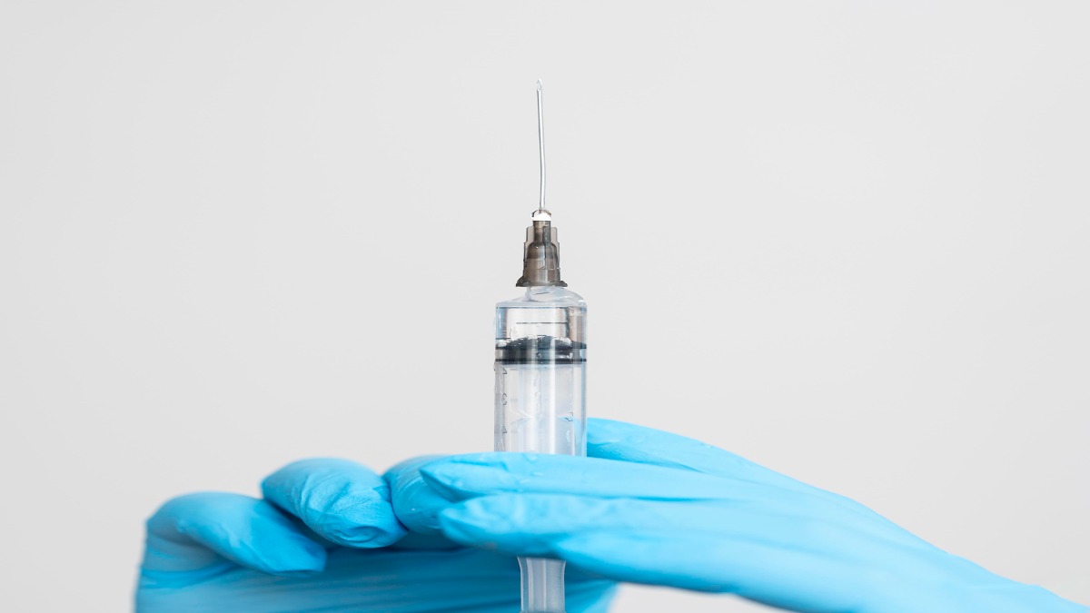Mão com luva azul segura seringa com a dose da vacina influenza trivalente registrada pela Anvisa, que teve eficácia de até 73% em adultos nos estudos clínicos