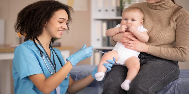 Enfermeira aplica vacina contra a gripe em bebê no colo da mãe, após a Anvisa registrar a vacina trivalente Fluprevli para uso a partir dos 6 meses de idade