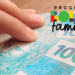 Mão segurando notas de 100 reais ao lado do logo do Bolsa Família.