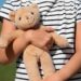 Imagem ilustrativa de criança de camiseta listrada segurando com os dois braços um urso de pelúcia, ao ar livre, referência à proteção legal reforçada para crianças e adolescentes