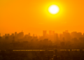 Pôr do sol intenso sobre metrópole com céu alaranjado.