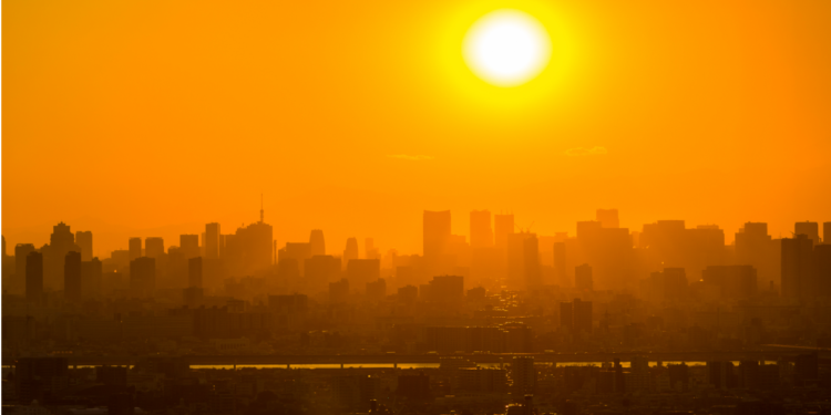 Pôr do sol intenso sobre metrópole com céu alaranjado.