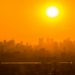 Pôr do sol intenso sobre metrópole com céu alaranjado.