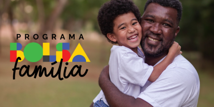 Homem adulto e criança sorridentes se abraçam ao ar livre ao lado do logo do Bolsa Família.