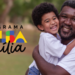 Homem adulto e criança sorridentes se abraçam ao ar livre ao lado do logo do Bolsa Família.
