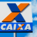 Placa da Caixa Econômica Federal com logo em destaque no céu.