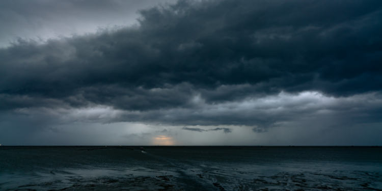 Nuvens de tempestade pesadas avançam sobre o mar ao entardecer.