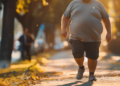 Homem caminhando ao ar livre em calçada urbana ao entardecer.