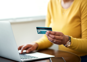 Mulher faz compra online utilizando cartão de crédito no notebook.