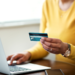 Mulher faz compra online utilizando cartão de crédito no notebook.