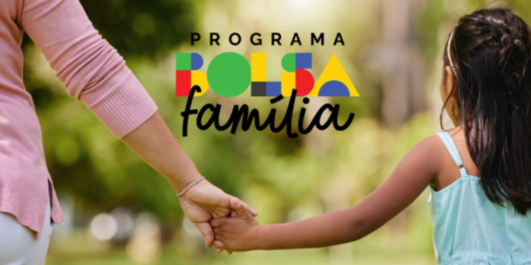 Mulher de blusa rosa e menina de trança de mãos dadas com logotipo do Bolsa Família ao fundo.