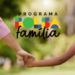 Mulher de blusa rosa e menina de trança de mãos dadas com logotipo do Bolsa Família ao fundo.