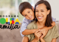 Mulher adulta e menino sorridentes no sofá ao lado do logo colorido do Programa Bolsa Família.