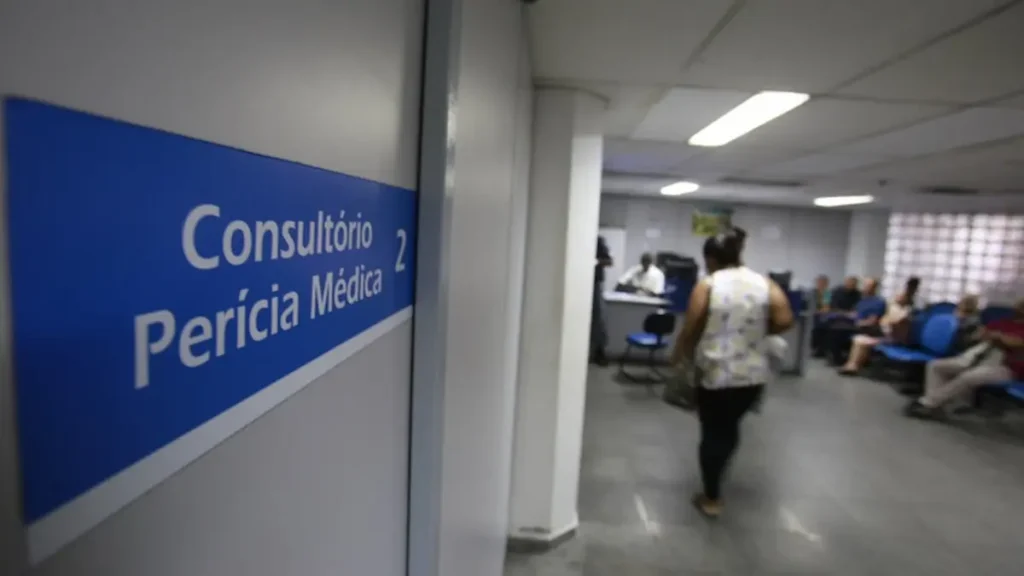 Sinalização "Consultório Perícia Médica 2" e pessoas aguardando em sala de espera ampla.