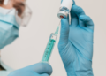 Profissional de saúde prepara seringa com vacina.